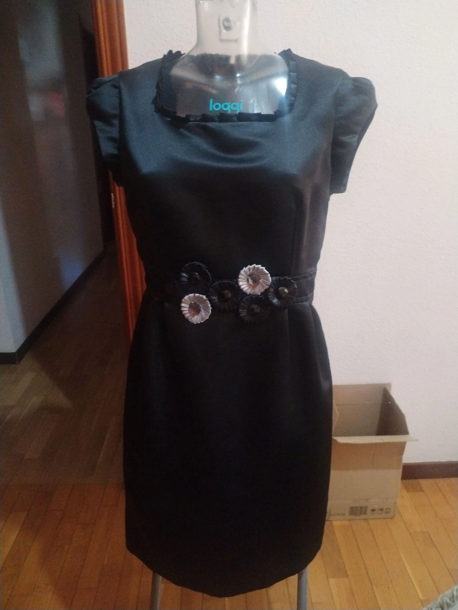 Un vestido de fiesta en negro con un toque en la cintura de flores y piedras